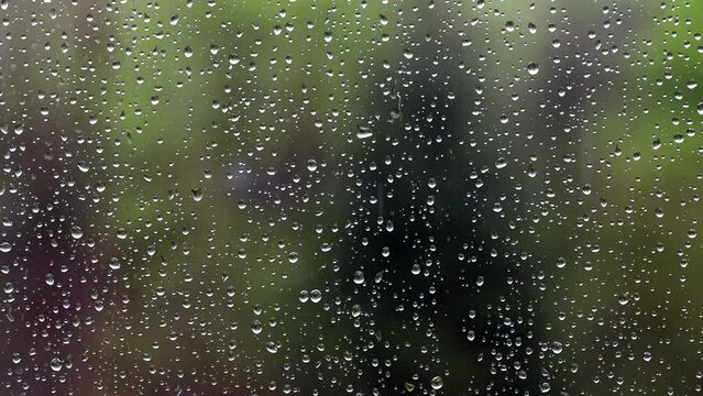 Raindrops fall on a window pane
