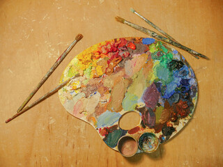 Colorful artist palette full of acrylic paint and with brushes