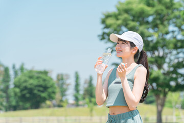 運動中に水・ミネラルウォーターを飲む女性（水分補給・運動・ワークアウト・ランニング・ウォーキング）
