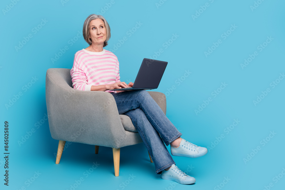 Canvas Prints Full length photo of pensioner lady armchair netbook look skeptical empty space dressed striped garment isolated on blue color background