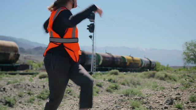 Male resource worker in the extractive industry dancing near the railway cars with oil, expressing satisfaction with the work done.