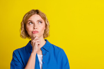 Portrait of pretty young lady look interested empty space wear blue shirt isolated on yellow color background