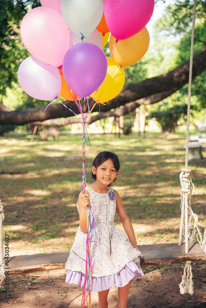 Wall mural cheerful cute girl holding balloons running on green meadow white cloud and blue sky with happiness.