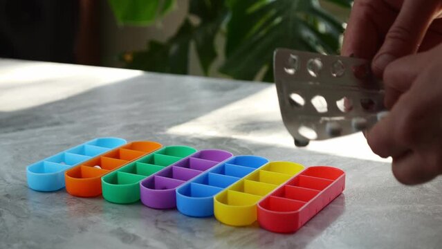 A weekly pillbox, for medication routine. A woman fills a weekly pillbox with medicines