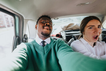 Two business colleagues sharing a fun and casual moment in the backseat of a car, portraying a...