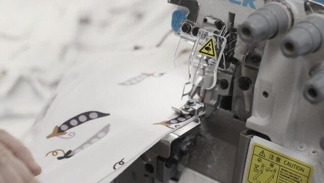 Closeup of an industrial sewing machine with fabric being stitched by expert hands