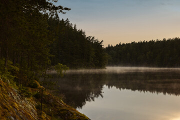 Frost smoke on a forest lake at sunset
