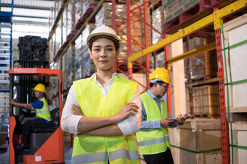 Portrait of Asian warehouse woman worker smile with arms crossed, Colleagues working and checking parcel box. export import or logistics service business. employee and labor factory