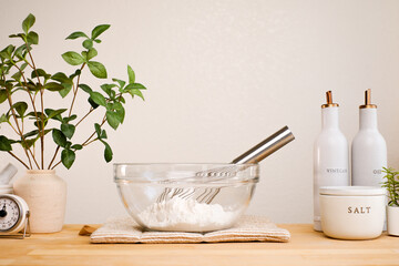 A beautiful kitchen countertop with a glass bowl of flour and a whisk, and small container for cooking or baking.