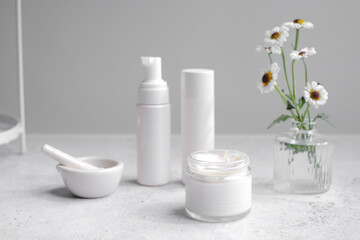 Skincare cosmetic products including a white pump bottle, two cylindrical containers, an open jar with cream. The beauty products, made of natural ingredients.