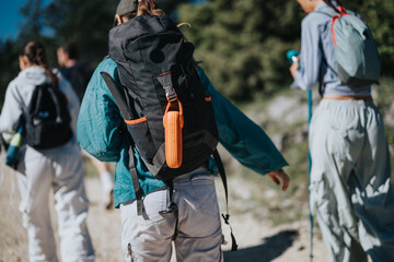 Group of friends hiking on a sunny day. They carry backpacks and walk together through a scenic outdoor trail.