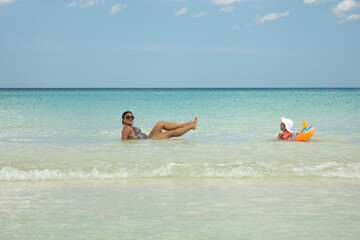 Obraz premium happy mother and her 2-year-old daughter enjoying the caribbean sea