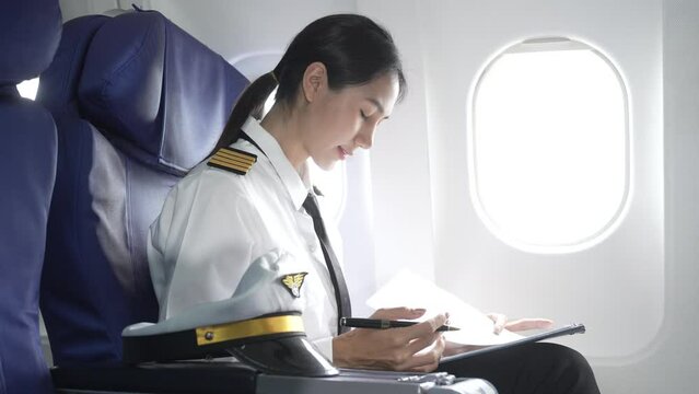 A female pilot in a blazer with epaulettes leans forward in the passenger seat of the airplane cockpit, checking the flight plan before takeoff, ensuring all pre-flight checks are complete.