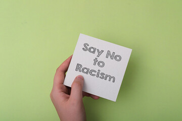 A hand holding a piece of paper that says Say No to Racism