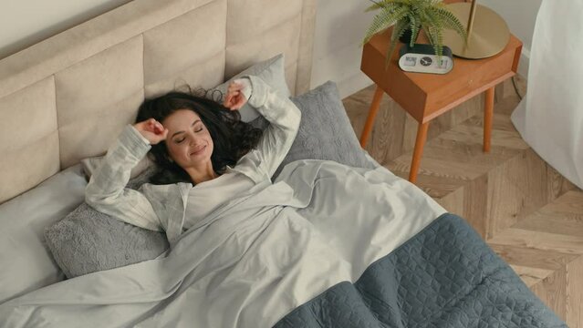 Happy woman stretching lying bed lazy comfortable girl female home hotel rest enjoyment smile good mood relaxed sleepy bedroom satisfaction pleasure weekend glad accommodation awaken daydream mattress