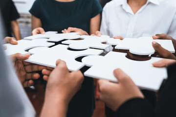 Diverse corporate officer workers collaborate in office, connecting puzzle pieces to represent...