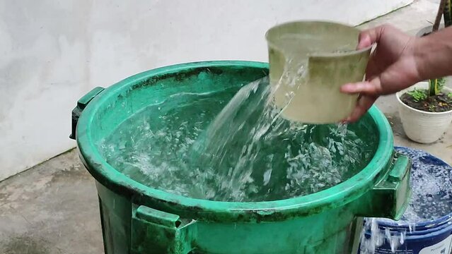 Rainwater is collected in a green water tank with a broken water scoop