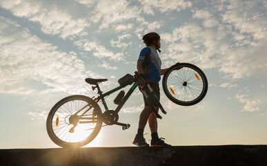 Man cyclist repairing a bike against the background of sky