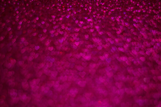 A close up of a pink background with many small hearts scattered throughout