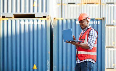 African factory worker or engineer working on laptop computer in containers warehouse storage