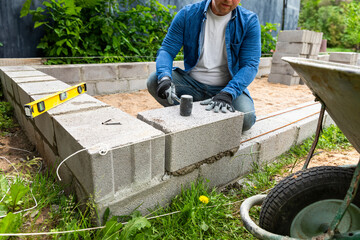 Construction worker laying expanded clay blocks. Foundations of a house, the frame of a new house in the process of construction