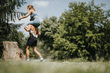 Two athletic friends engaging in a dynamic exercise routine together outdoors in a park, showing strength and teamwork.