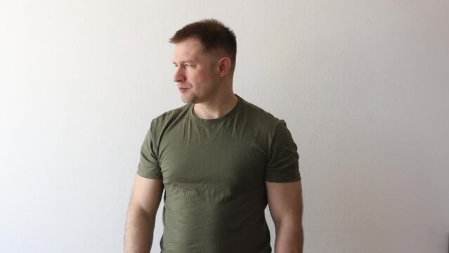 A man in a military hacky sack t-shirt salutes with his hand. 