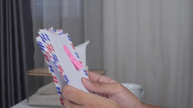side view close up of hands sorting envelopes on table with curtain background