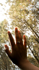 A girl showing her ring and raise it to the sky, in the middle forest, and lighten by sunset