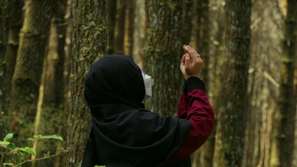 Fototapeta premium Hijabi Muslimah, serene in forest, finds solace, bowing in prayer, amidst nature's embrace