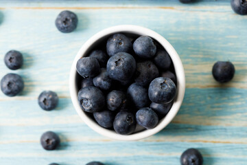 Ripe organic blueberries on blue wooden table background. Selective focus.