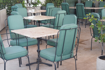 The restaurant has tables and chairs with green cushions for comfort