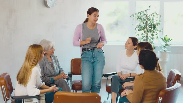 Positive young girl participating in volunteer organization talking with interest about new project to group of female partners of different ages during informal meeting
