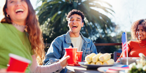 Friends, celebration and independence day in USA with backyard food, drinks and international holiday. Social group of people with American Flag, barbecue and lunch at patio table for fourth of July