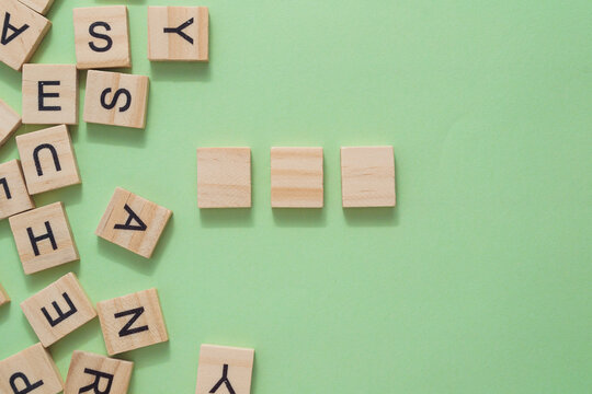 Three wooden blocks are on a green background with the letters