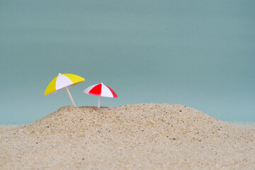 Miniature beach umbrella on beach sand with copy space
