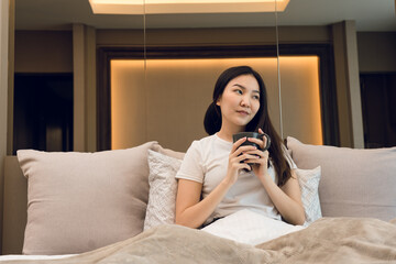 Asian woman holding a cup of coffee in the morning after waking up.