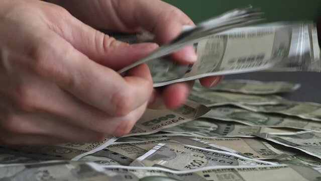 Woman's hands counting brand new indian 500 rupees banknotes.