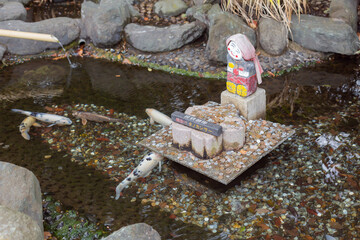 colorful corps swimming in the pond with a small stone sculpture in sakuragi shinto shrine