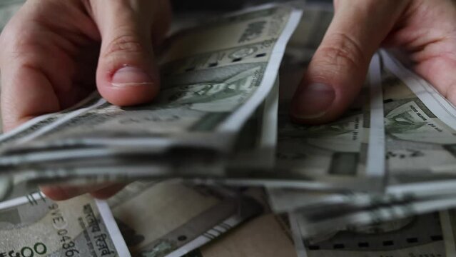 Woman's hands counting brand new indian 500 rupees banknotes.
