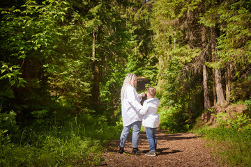 Funny mother with dreadlocks and fat boy happy walking in the woods on a sunny summer day