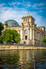 Teilansicht des Reichstagsgebäudes, im Vordergrund die Spree, leicht bewölkter blauer Himmel, vertikal