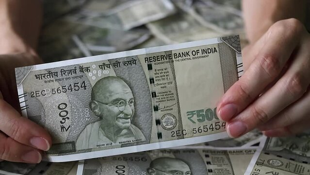 Woman's hands holding brand new indian 500 rupees banknote.