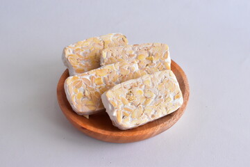 Raw Tempeh or Tempe. Tempeh Slices on Wooden White Background. Tempe Made From Fermented Soybeans