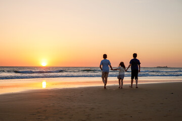 Three kids silhouettes running and jumping on beach at sunset. happy family, two school boys and one little preschool girl. Siblings having fun together. Bonding and family vacation.