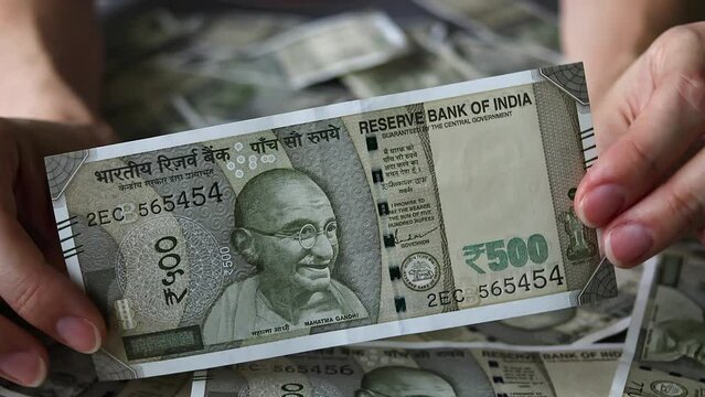 Woman's hands holding brand new indian 500 rupees banknote.
