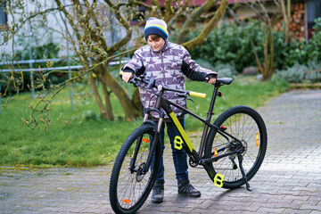 Fototapeta premium Handsome preteen boy going to school on bike. Teenager ride bicycle. Safe way to high school. Happy child boy with backpack on bike. Healthy outdoor activity for young student.