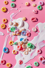 A top-down view of colorful cereal and spilled milk on a pink background. Modern food aesthetic.