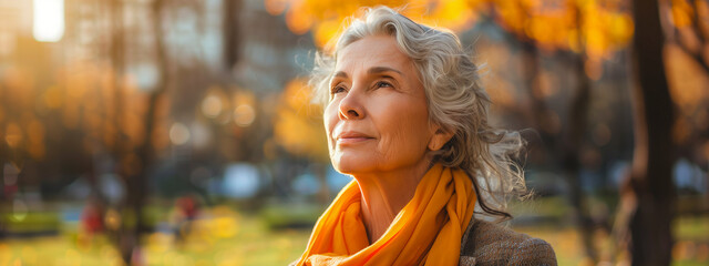 An elderly woman with gray hair looks content while basking in the warm autumn sunlight, with a backdrop of golden foliage ,generative ai