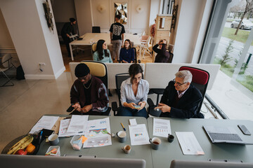 A modern office meeting with diverse colleagues. Includes a creative workspace, engaging discussions, and relaxed atmosphere captured from above.